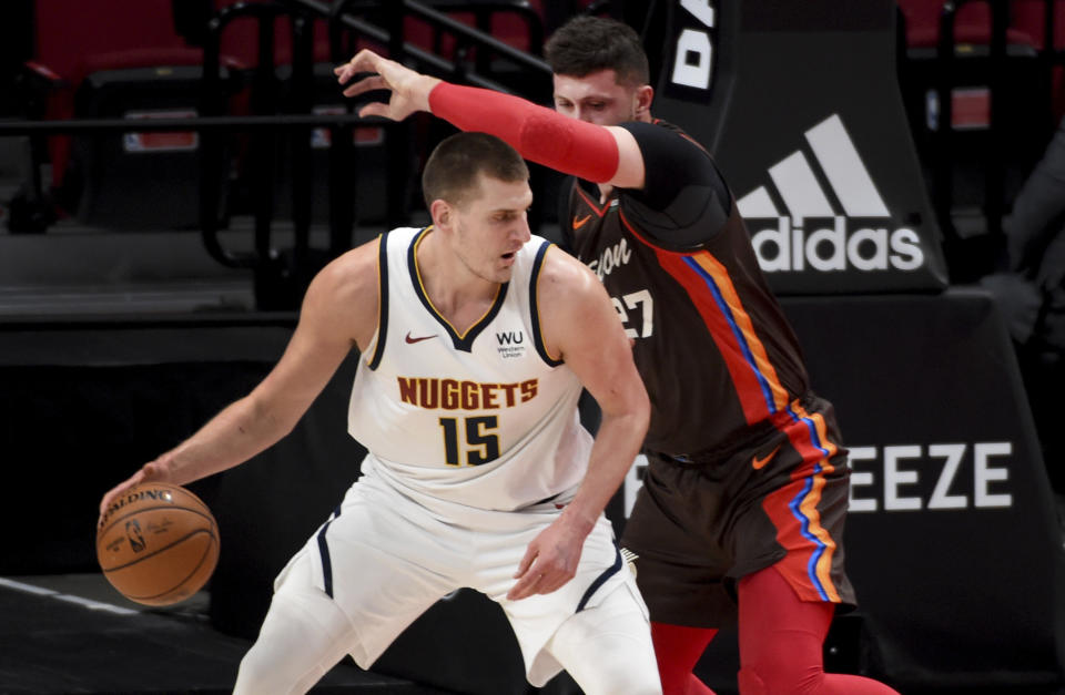 Denver Nuggets center Nikola Jokic, left dribbles the ball on Portland Trail Blazers center Jusuf Nurkic, right, during the first half of an NBA basketball game in Portland, Ore., Sunday, May 16, 2021. (AP Photo/Steve Dykes)