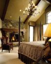 <p>An elegant master bedroom features wood beams, a stone fireplace and four-poster bed. The traditional chandelier is a great finishing touch. Design by <a href="https://deringhall.com/architects/brewster-mcleod-architects" rel="nofollow noopener" target="_blank" data-ylk="slk:Brewster McLeod Architects;elm:context_link;itc:0;sec:content-canvas" class="link ">Brewster McLeod Architects</a>. </p>