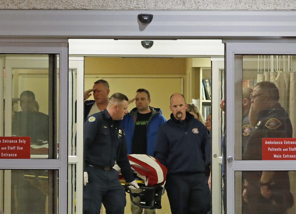 Fire and law enforcement officials join others in saluting as the body of a Kittitas County Sheriff's deputy draped with a U.S. flag is carried out of Kittitas Valley Healthcare Hospital, in the early morning hours of Wednesday, March 20, 2019, in Ellensburg, Wash. A Kittitas County Sheriff's deputy was killed and a police officer was injured after an exchange of gunfire during an attempted traffic stop. (AP Photo/Ted S. Warren)