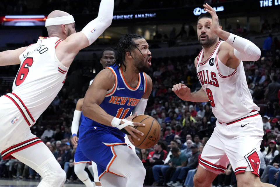 New York Knicks guard Jalen Brunson, center, drives to the basket against Chicago Bulls guard Alex Caruso, left, and center Nikola Vucevic during the first half of an NBA basketball game in Chicago, Tuesday, April 9, 2024. (AP Photo/Nam Y. Huh)