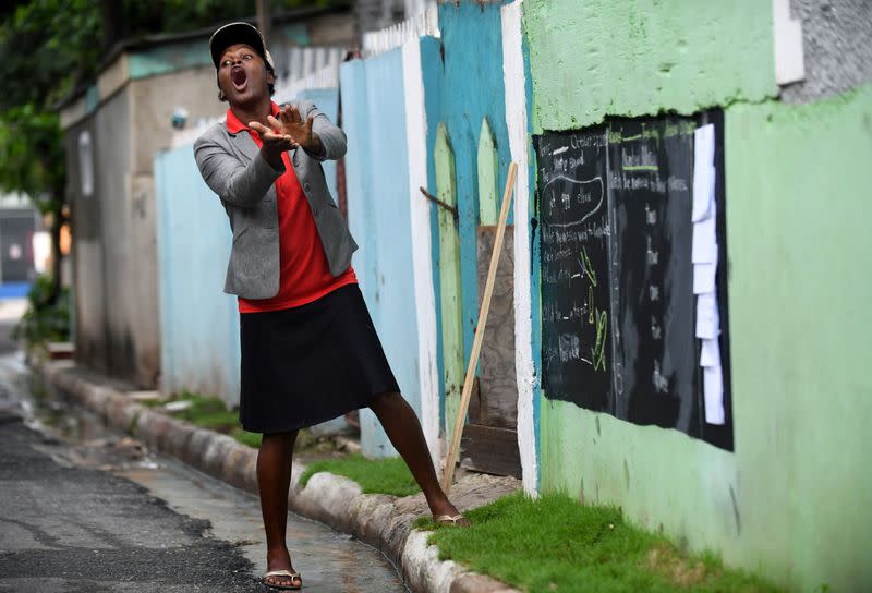 Educator Mckoy Phipps teaches a lesson with a blackboard painted on a wall during the coronavirus disease (COVID-19) outbreak in Kingston