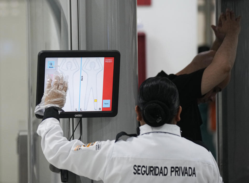 FILE - A security officer checks a passenger via a body scanner at a check point at the Benito Juarez International Airport, in Mexico City, Friday, June 30, 2023. Mexico's armed forces are taking control of the capital's main airport and the government plans to give the military control of nearly a dozen more across the country as the president aims at corruption and mismanagement. (AP Photo/Fernando Llano, File)