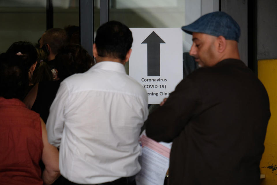 People wait in line to be screened for COVID-19 outside the Royal Melbourne Hospital.