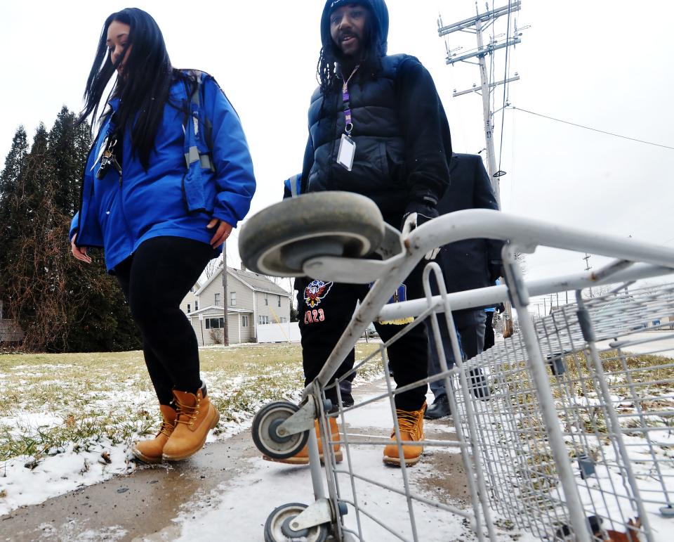 Blue Coats members Taylor Yahner, left, and Roscoe Carroll help highlight the need for safe walking routes for students in Erie on Tuesday as they stroll past an overturned shopping cart on a sidewalk on East Lake Road.