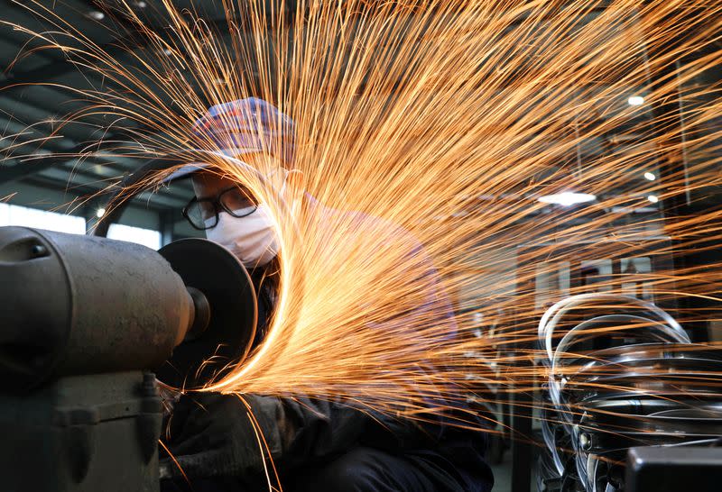 Worker wearing a face mask works on a production line manufacturing bicycle steel rim at a factory in Hangzhou, Zhejiang