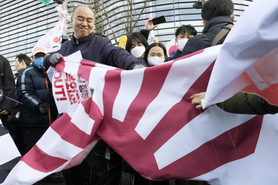 Protesters tear a banner with the Japanese rising sun flag during a rally against the South Korean government's move to improve relations with Japan in front of the Japanese Embassy in Seoul, South Korea, Wednesday, March 1, 2023. South Korea's president on Wednesday called Japan "a partner that shares the same universal values" and renewed hopes to repair ties frayed over Japan's colonial rule of the Korean Peninsula. (AP Photo/Ahn Young-joon)
