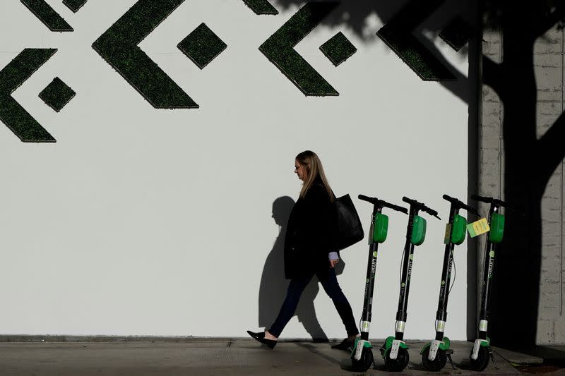 FILE PHOTO: A woman walks past electric Lime scooters parked on the sidewalk in downtown Los Angeles, California