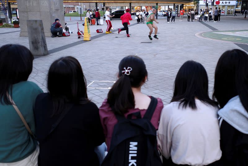 FILE PHOTO: Girls watch a music performance by street buskers in Oita