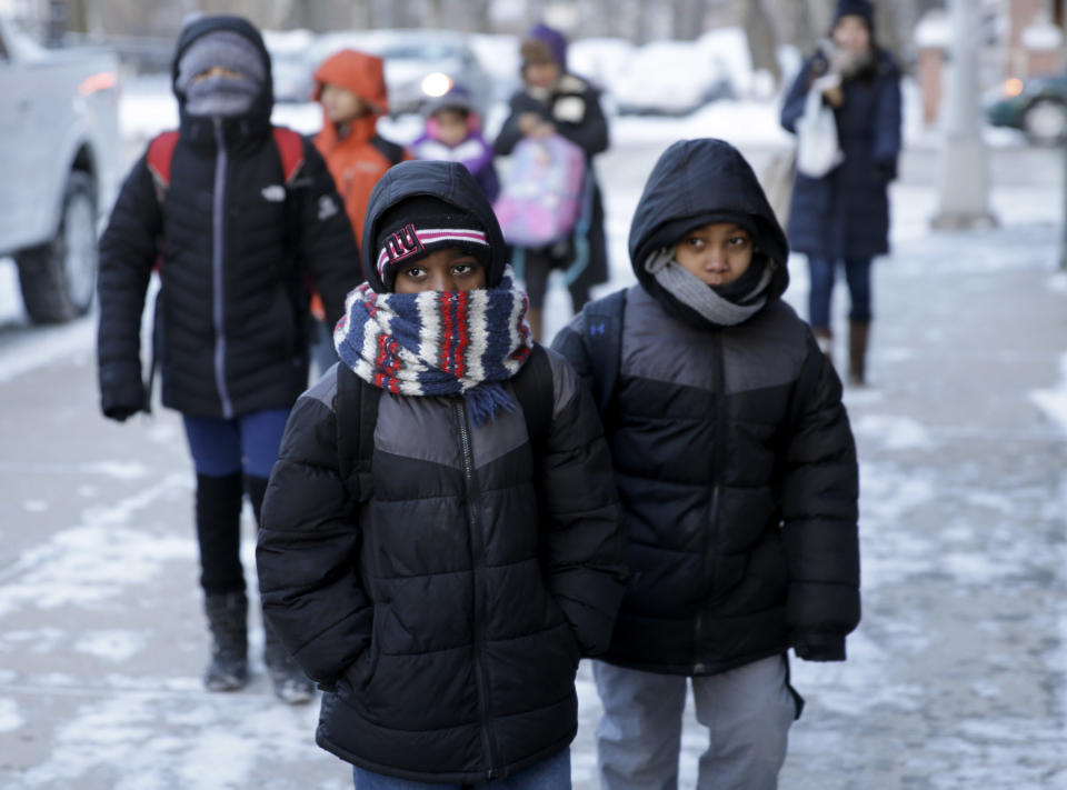 Children arrive to school bundled up against the cold in the Brooklyn borough of New York, Wednesday, Jan. 22, 2014. A winter storm stretched from Kentucky to New England and hit hardest along the heavily populated Interstate 95 corridor between Philadelphia and Boston. Snow began falling at midmorning Tuesday in Philadelphia and dumped as much as 14 inches by Wednesday morning, with New York seeing almost as much. Boston and Philadelphia officials ordered schools closed Wednesday, but in New York City, the nation's largest public school system remained open. (AP Photo/Seth Wenig)