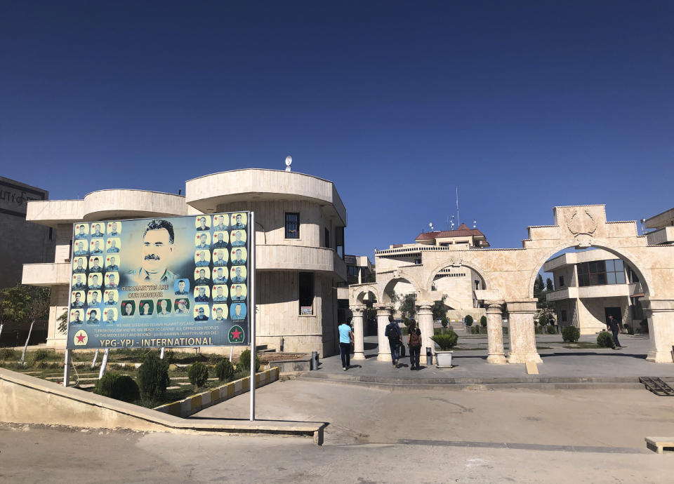 A giant banner shows a portrait of the jailed leader of the Kurdistan Workers' Party, or PKK, Abdullah Ocalan, center, with other portraits of killed Kurdish fighters, set at the border crossing between Iraq and Syria's Kurdish-held, in Semelka, northeast Syria, Monday Oct. 14, 2019. (AP Photo/Hussein Malla)