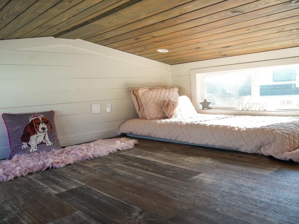 The loft has a kid-sized pink bed and a window on the right