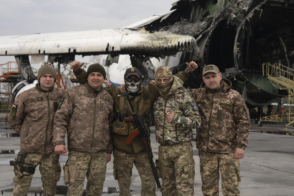 Ukrainian soldiers of mobile air defence units pose for a photo at the Antonov airport, in front of the gutted remains of the Antonov An-225, the world's biggest cargo aircraft, destroyed during fighting between Russian and Ukrainian forces, in Hostomel, on the outskirts of Kyiv, Ukraine, Saturday, April 1, 2023. (AP Photo/Efrem Lukatsky)