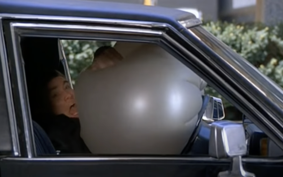 A man fighting an air bag in a car