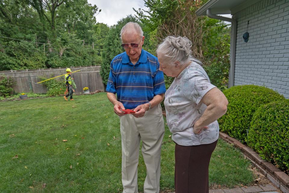 Bill and Barbara Conlin look at a paper given to them about tree trimming and emergency work Monday, July 3, 2023.  Meade (out of Chicago) and Wright Tree Service work on areas without power on Camelback Drive and the area behind the Conlin home. The companies are contracted by AES. The Conlins have been without power since Thursday night.