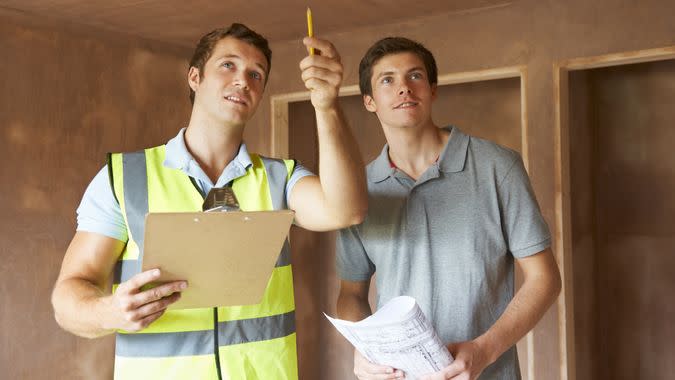 Builder And Inspector Looking At New Property.