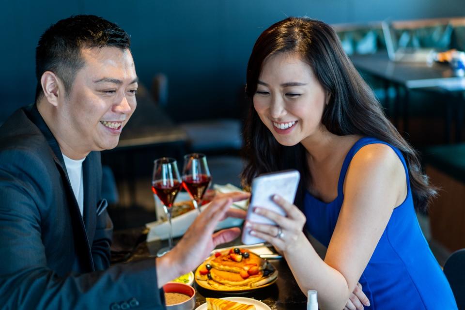 A couple share information with a smart phone during a date. A survey commissioned by dating app Coffee Meets Bagel (CMB) found that common social causes are important in forging successful long-term relationships. (Photo: Getty Images)