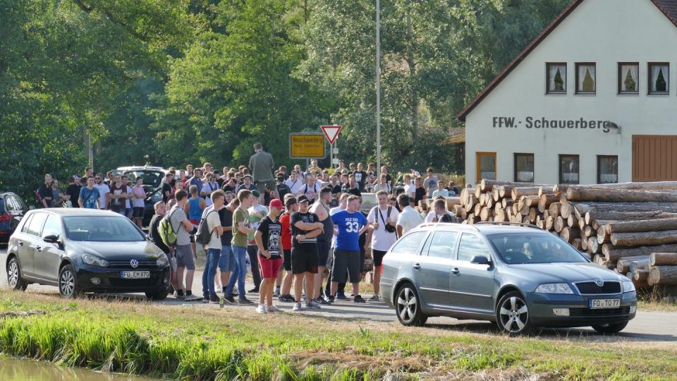 Menschen versammeln sich, stehen zwischen Autos