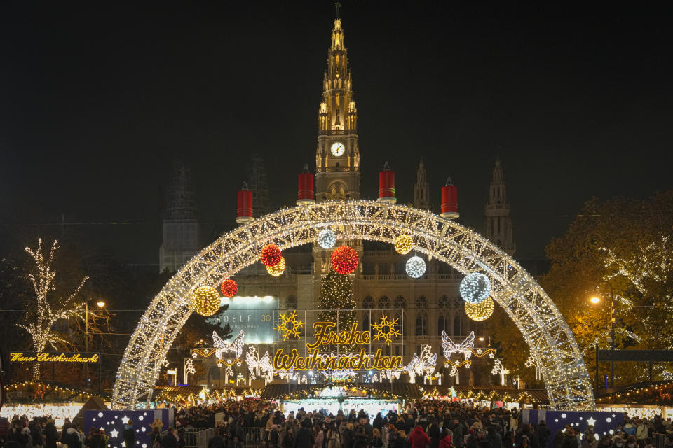 People crowd a Christmas market, backdropped by the city hall building, in Vienna, Austria, Sunday, Nov. 21, 2021. The Austrian government announced a nationwide lockdown that will start Monday and comes as average daily deaths have tripled in recent weeks and hospitals in heavily hit states have warned that intensive care units are reaching capacity.(AP Photo/Vadim Ghirda)