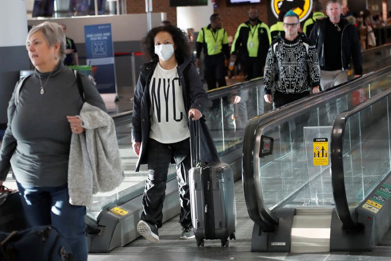 A woman walks with a face mask, after further cases of coronavirus were confirmed in New York, at JFK International Airport in New York