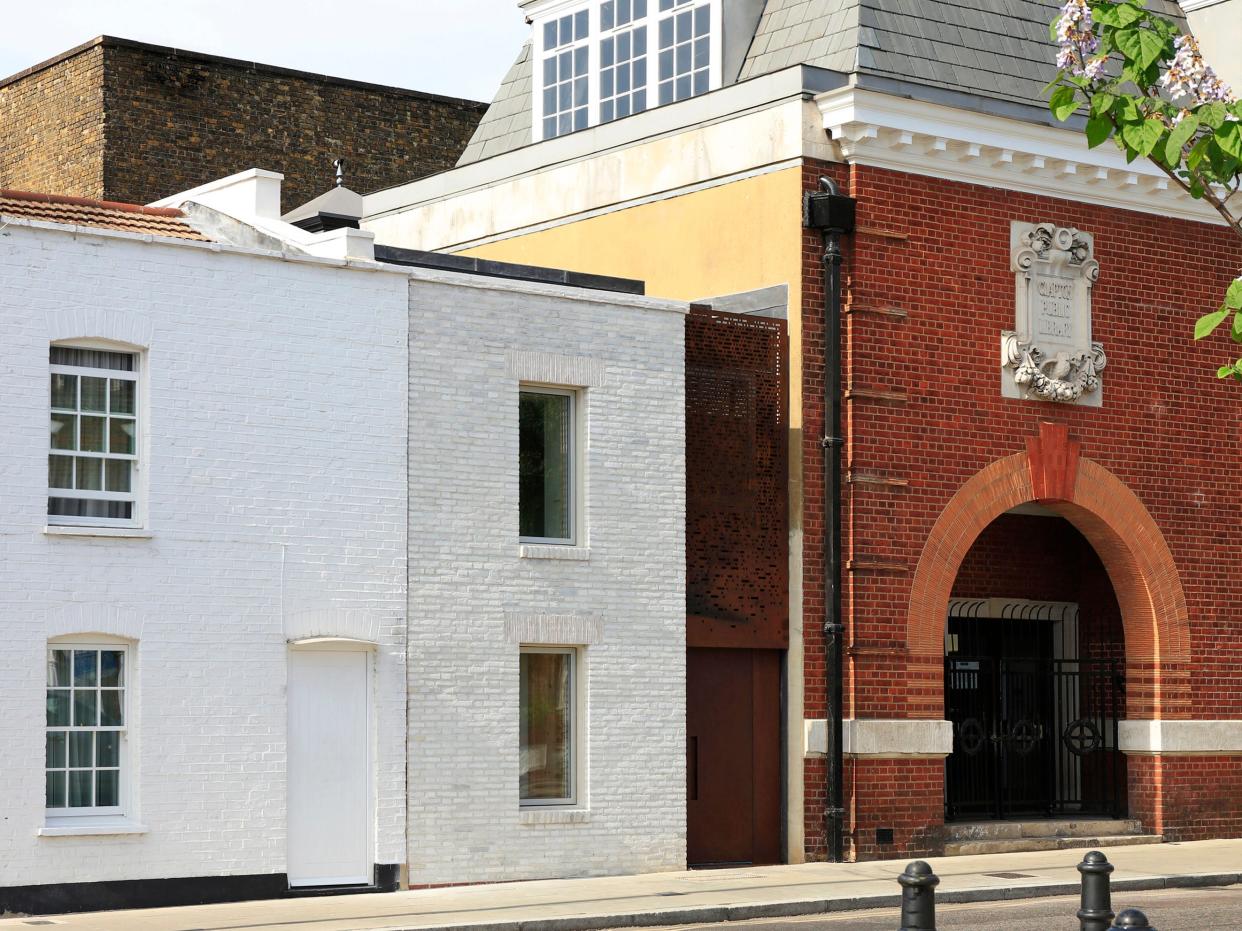 The front of the house dramatically shifts design halfway along, with white brickwork complementing the Victorian home to its right while a rusty steel feature melts into the library on the home’s left.