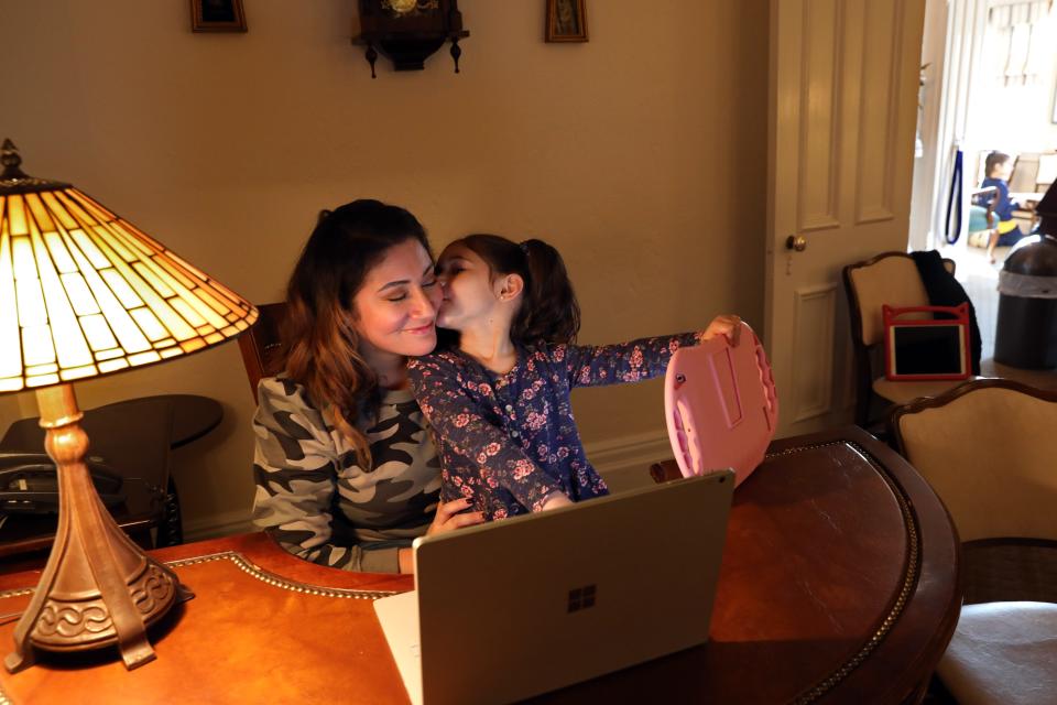 Leslie Chiaramonte gets a kiss from her daughter Phoenix, 3, at the Nardone Funeral Home, the family business in Peekskill, N.Y., on Feb. 25, 2021. Leslie quit her job as a nurse last fall because of hybrid learning to stay home with her two children. Now, she is pursuing her funeral director license so she can help her husband out in the family business.