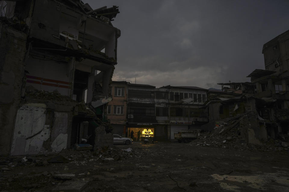 A group of people stand next to a jewellery shop amid damaged buildings that were destroyed by a powerful earthquake in Antakya, southern Turkey, Friday, Jan. 12, 2024. A year after the earthquake hit, many in the region are struggling to rebuild lives. (AP Photo/Khalil Hamra)