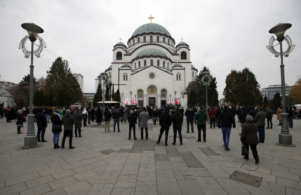 Believers stand in front of St. Sava Temple during the funeral procession of Patriarch Irinej in Belgrade, Serbia, Sunday, Nov. 22, 2020. The 90-year-old Irinej died early on Friday, nearly three weeks after he led the prayers at a funeral of another senior church cleric in neighboring Montenegro, who also died after testing positive for the virus. (AP Photo/Darko Vojinovic)