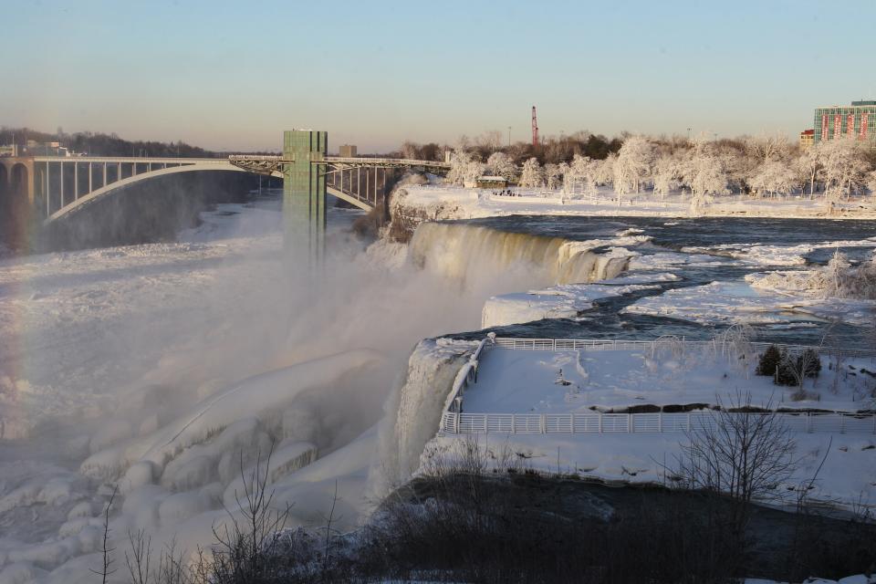 The area surrounding Niagara Falls is coated in a layer of ice in Niagara Falls State Park, Niagara Falls, N.Y. on Thursday, Jan. 9, 2014. Niagara Falls hasn't frozen over, but it has become an icy spectacle, thanks to a blast of arctic wind and cold that blew around and froze the mist on surfaces and landscaping. Despite the urban legends, Niagara Falls doesn't freeze solid in the winter, tourism officials say. A section of the American Falls, one of three waterfalls that make up the natural attraction, has frozen. The Niagara River rapids and larger Horseshoe Falls continue to flow unimpeded. (AP Photo/The Buffalo News, Sharon Cantillon) MANDATORY CREDIT