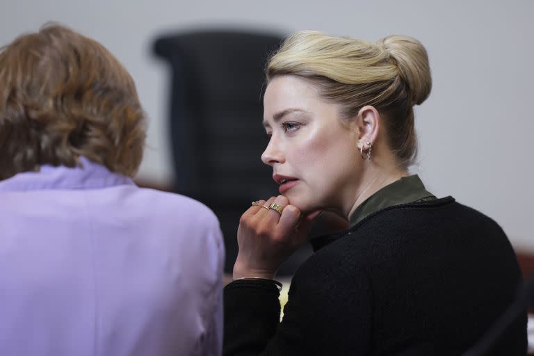 La actriz Amber Heard habla con una miembro de su equipo legal en el Tribunal de Circuito del Condado de Fairfax (Evelyn Hockstein/Pool photo via AP)