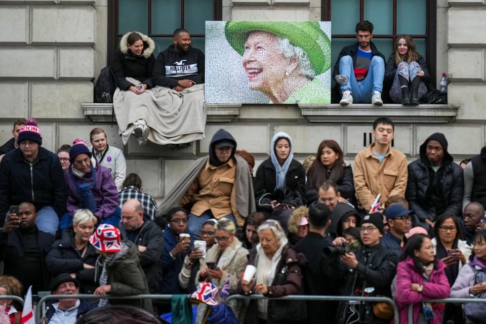 People wait along the route that the coffin of Queen Elizabeth II will be pulled on a gun carriage following her funeral service in Westminster Abbey (AP)