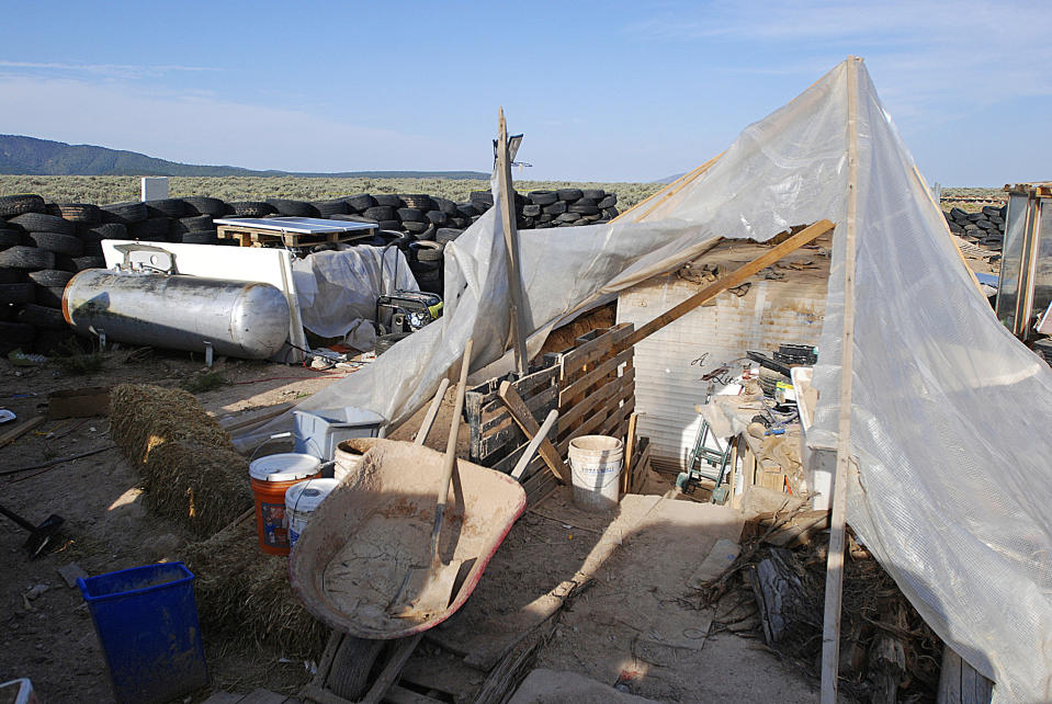 FILE - This Aug. 10, 2018 file photo shows various items littering a squalid makeshift living compound in Amalia, N.M. Five former residents of a New Mexico compound where authorities found 11 hungry children and a dead 3-year-old boy are due in federal court on terrorism-related charges. The two men and three women living at the compound raided in August are being arraigned Thursday, March 21, 2019, on new charges of supporting plans for violent attacks. (AP Photo/Morgan Lee, File)