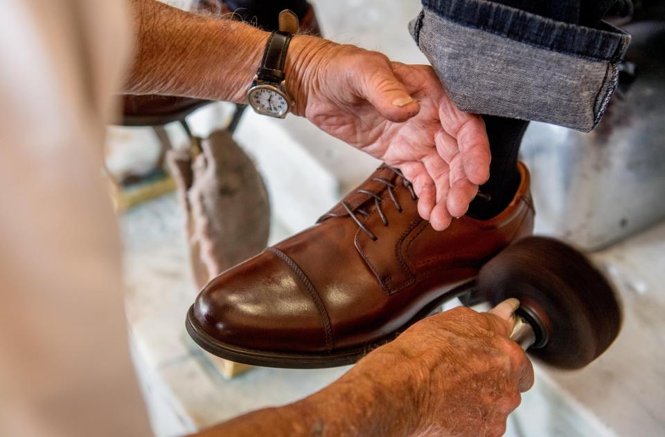 George Manias of George's Shoeshine and Hatters runs a buffer on a pair of shoes at his shop in Downtown Peoria.