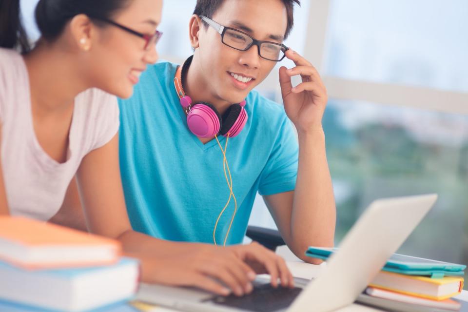 Two college students watching content on a shared laptop.