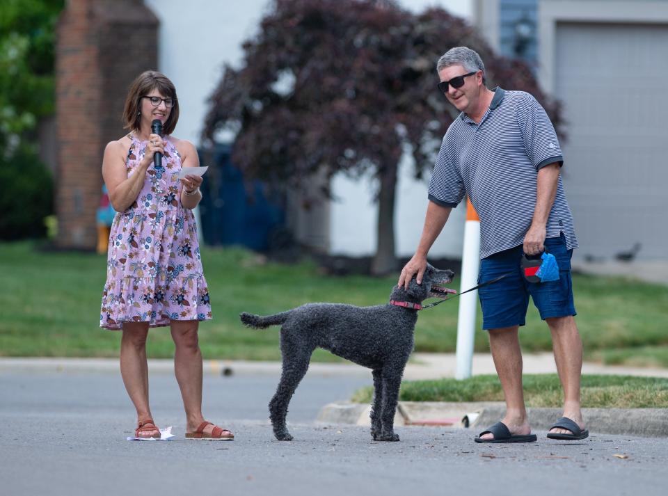 Host Kim Emch (left) introduces Greg Kramer and Shae, a 13-year-old standard poodle and retired therapy dog, during the River Landings subdivision dog show June 26.