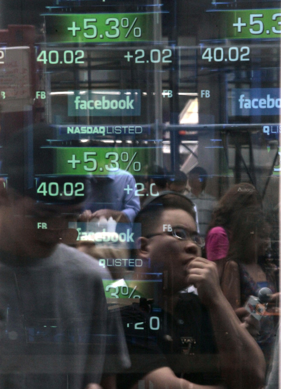 FILE- In this Friday, May 18, 2012, file photo, Passers-by are reflected in the window of the Nasdaq media center as they view reports of trading activity on Facebook's stock on the Nasdaq stock market in New York. It’s been a month since Facebook’s IPO fell flat and in that time, the market for initial public offerings has gone cold. Venture capitalists say the fallout from Facebook’s rocky IPO is making technology companies more cautious about going public.(AP Photo/Bebeto Matthews, File)