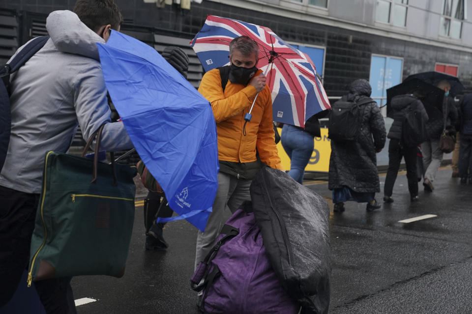 Delegates try to cope with the wet weather conditions as the wait to enter the Scottish Event Campus ahead of the COP26 Summit in Glasgow, Scotland, Sunday October 31, 2021. (Owen Humphreys/PA via AP)