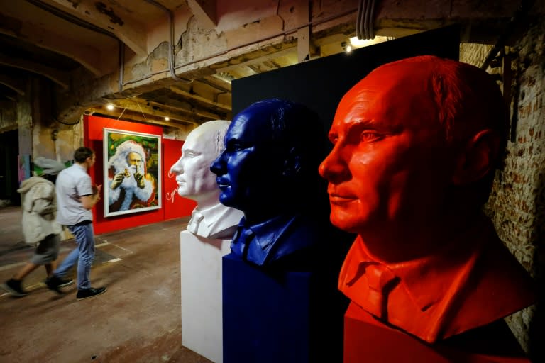 Visitors walk past paintings and busts depicting Russian President Vladimir Putin at the "SUPERPUTIN" exhibition at UMAM museum in Moscow on December 6, 2017