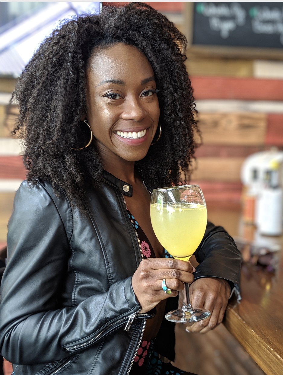 A woman sitting at a table posing with a drink in her hand