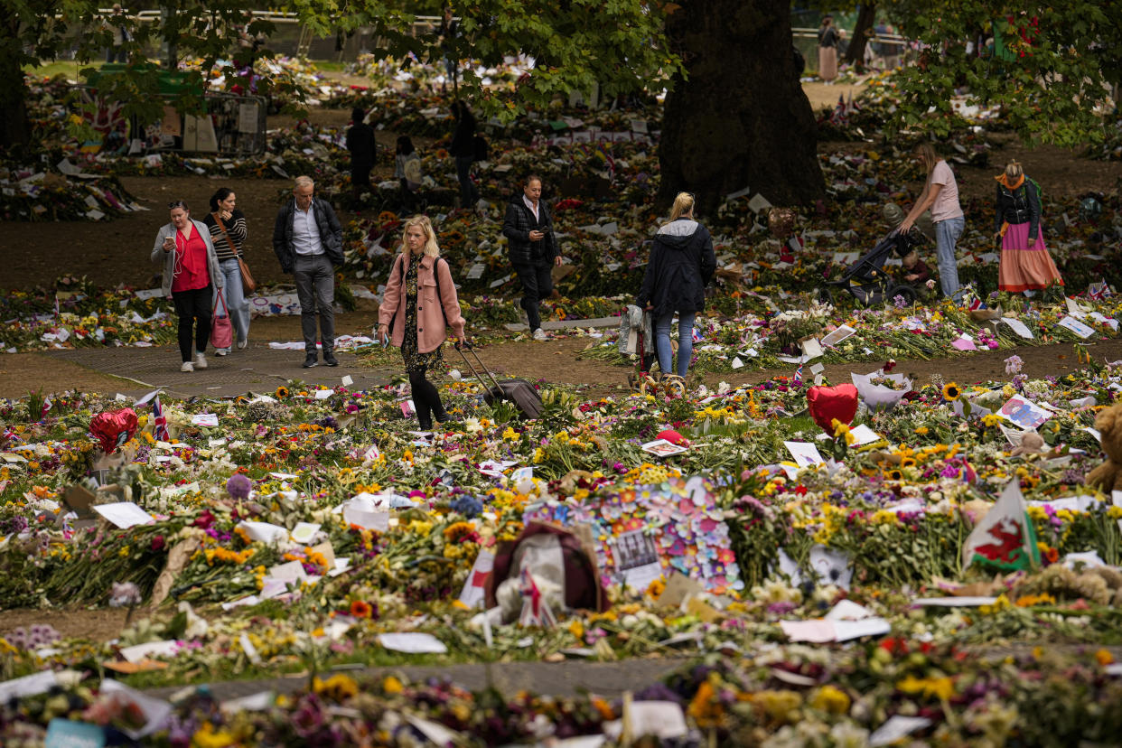 People bring floral tributes Queen Elizabeth II the day after her funeral, in London's Green Park, Tuesday, Sept. 20, 2022. The Queen, who died aged 96 on Sept. 8, was buried at Windsor alongside her late husband, Prince Philip, who died last year. (AP Photo/Vadim Ghirda)