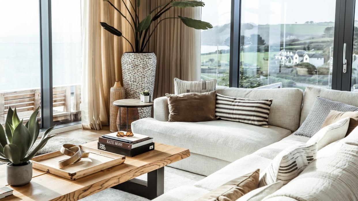  A living room with oversized stuffed white sofa, a wooden coffee table with styled books, and small round black side table 