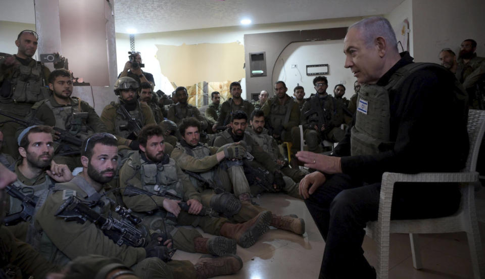 Israel's Prime Minister Benjamin Netanyahu, right, speaks to soldiers as he visits the northern Gaza Strip, where he received security briefings with commanders and soldiers, on Monday, Dec. 25, 2023. (Avi Ohayon/GPO/Handout via AP)