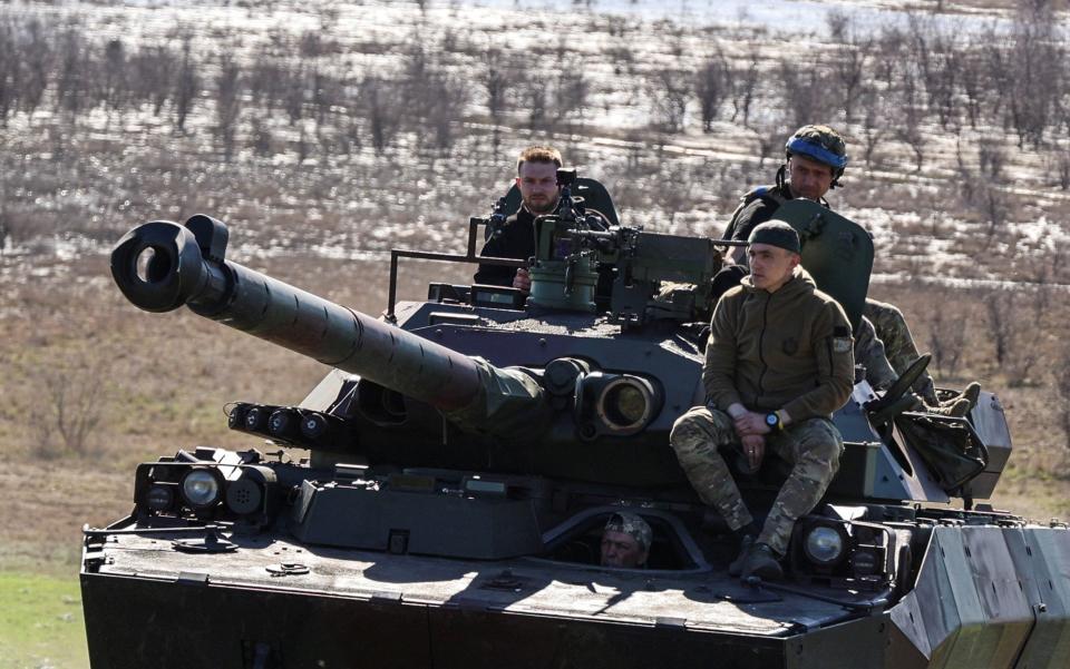 Service members of the 37th Marine Brigade of the Ukrainian Armed Forces ride atop a French armoured fighting vehicle in southern Ukraine