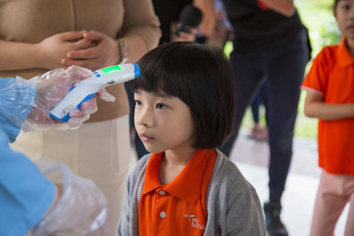 A pre-schooler gets her temperature tested at the My First Skool branch in Buangkok Crescent on Tuesday (28 January). (PHOTO: Dhany Osman / Yahoo News Singapore)