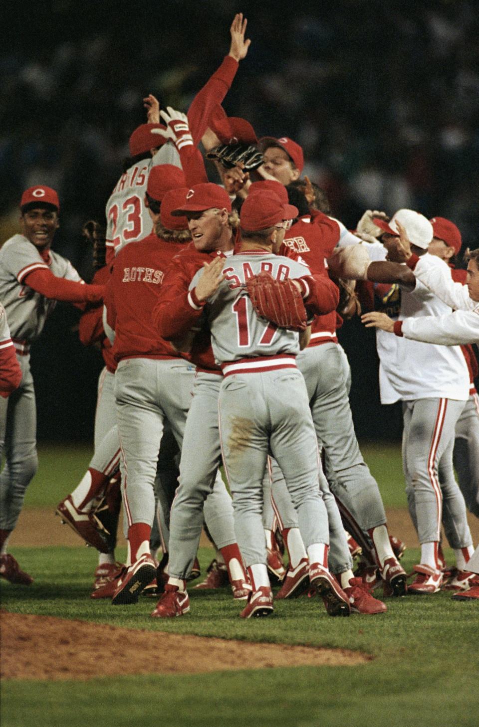 Members of Cincinnati Reds celebrate on the field of Oakland Coliseum following their 2-1 win over the Oakland Athletics which clinched the World Series, Oct. 20, 1990. At center is Chris Sabo as teammate Billy Hatcher, at right wearing white shirt and hat, joins him.