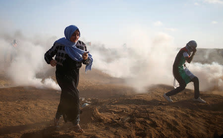 Palestinians run from tear gas fired by Israeli troops during a protest calling for lifting the Israeli blockade on Gaza and demand the right to return to their homeland, at the Israel-Gaza border fence, east of Gaza City September 14, 2018. REUTERS/Mohammed Salem