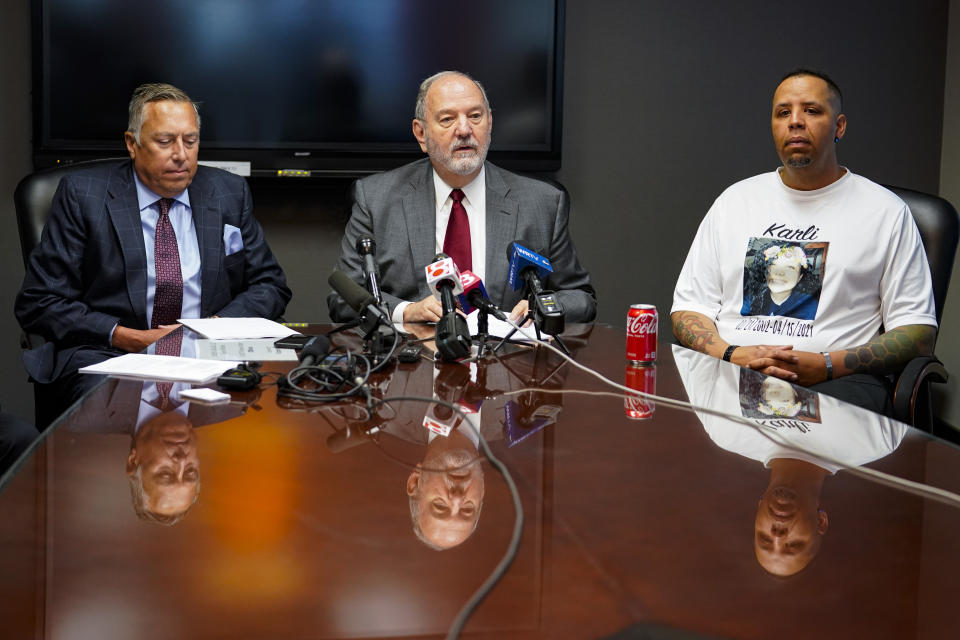 Attorneys Daniel Chamberlain, left, and Melvin Hewitt, Jr., center, along with family member Matthew Alexander announce a lawsuit in Indianapolis, Monday, April 11, 2022 on behalf of five families of the victims murdered in a mass shooting at the Indianapolis FedEx Ground facility on April 15, 2021. Alexander's daughter, Karli Smith, was was one of eight workers killed in the shooting. (AP Photo/Michael Conroy)