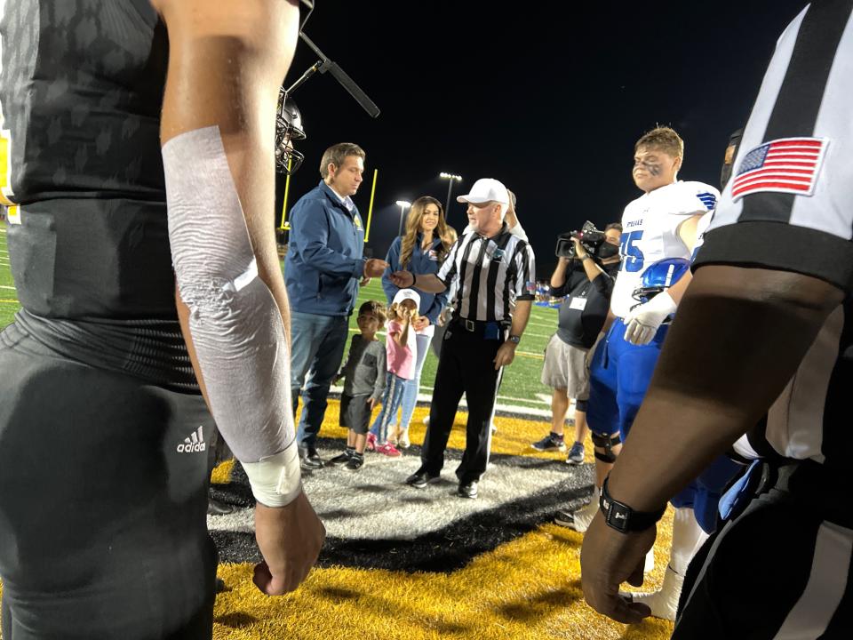 Gov. Ron DeSantis does the coin flip before the Sebring at Merritt Island Class 5A state semifinal football game on Friday night on Merritt Island. DeSantis was their with his wife Casey and their children.