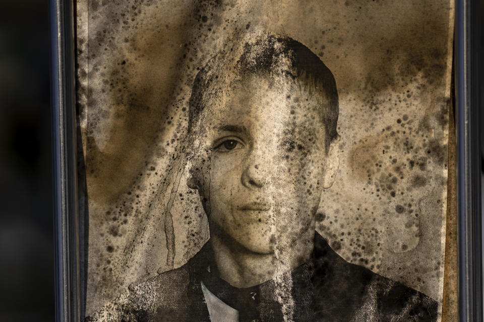 A worn-out portrait of Dmytro Andriyovych, 34, sits on his grave at a cemetery in Irpin, Ukraine, on the outskirts of Kyiv, on Friday, Feb. 10, 2023. He was buried on April 26, 2022. Exposed to rain, sun and frost over the course of a war that began nearly a year ago, the graveside portraits' once bright hues are fading away and yellow stains and mold are encroaching. (AP Photo/Emilio Morenatti)