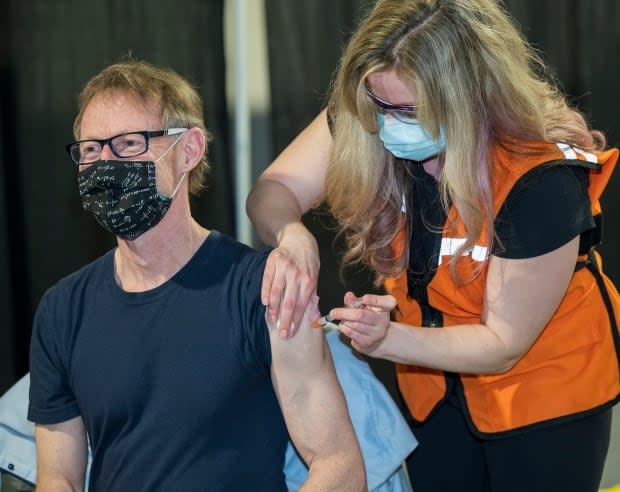 Yukon's Chief Medical Officer of Health, Dr. Brendan Hanley receives his COVID-19 vaccine from nurse Angie Bartelen at the Yukon Convention Centre in Whitehorse on March 3.