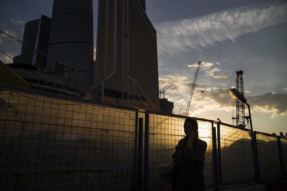 <p>A woman walks along a fence next to Moscow’s skyscrapers during sunset in Moscow, May 18, 2017. (Photo: Alexander Zemlianichenko/AP) </p>